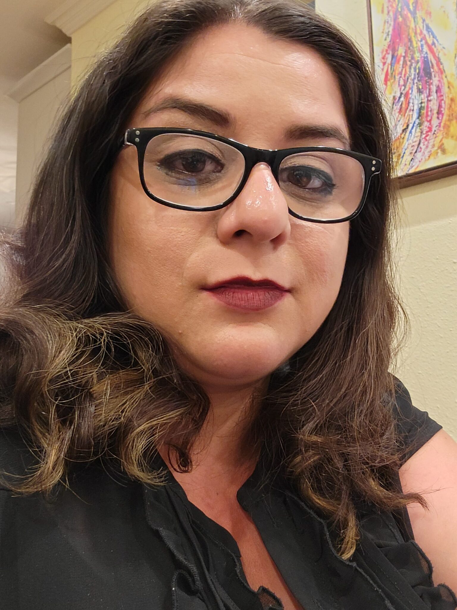 LGBTQ2IA, LGBTQ therapist with black thick framed glasses, wearing a black shirt, staring at the camera. Therapist.
